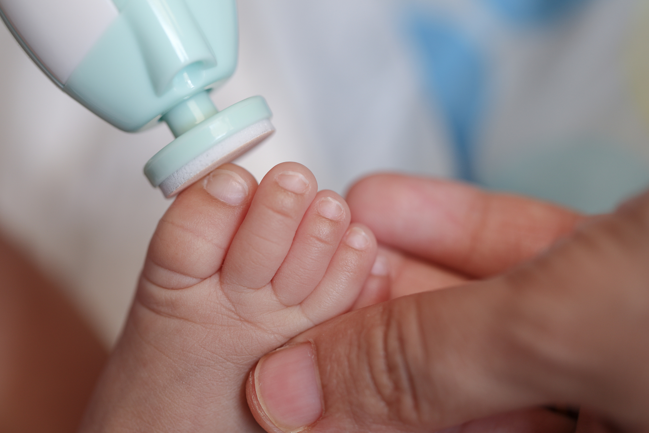 Cut nails with nail file, Mother filling baby nails using Automatic baby nail file machine.