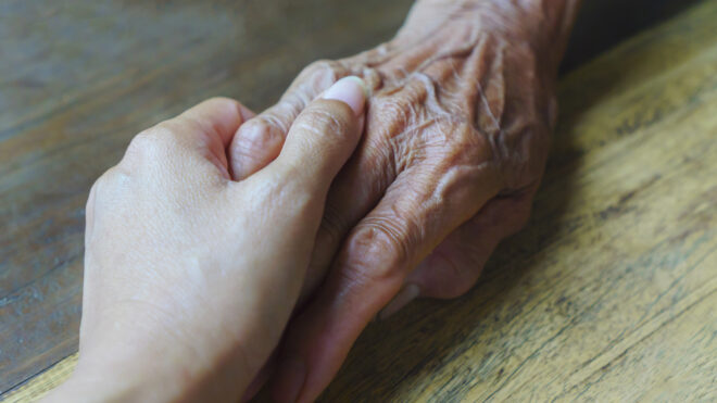 young woman hand holds old woman's hand