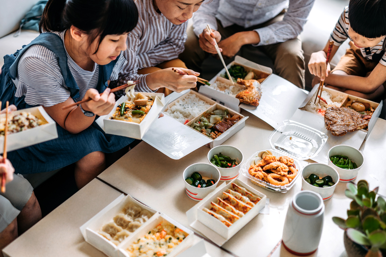 Asian family eating takeout food in living room