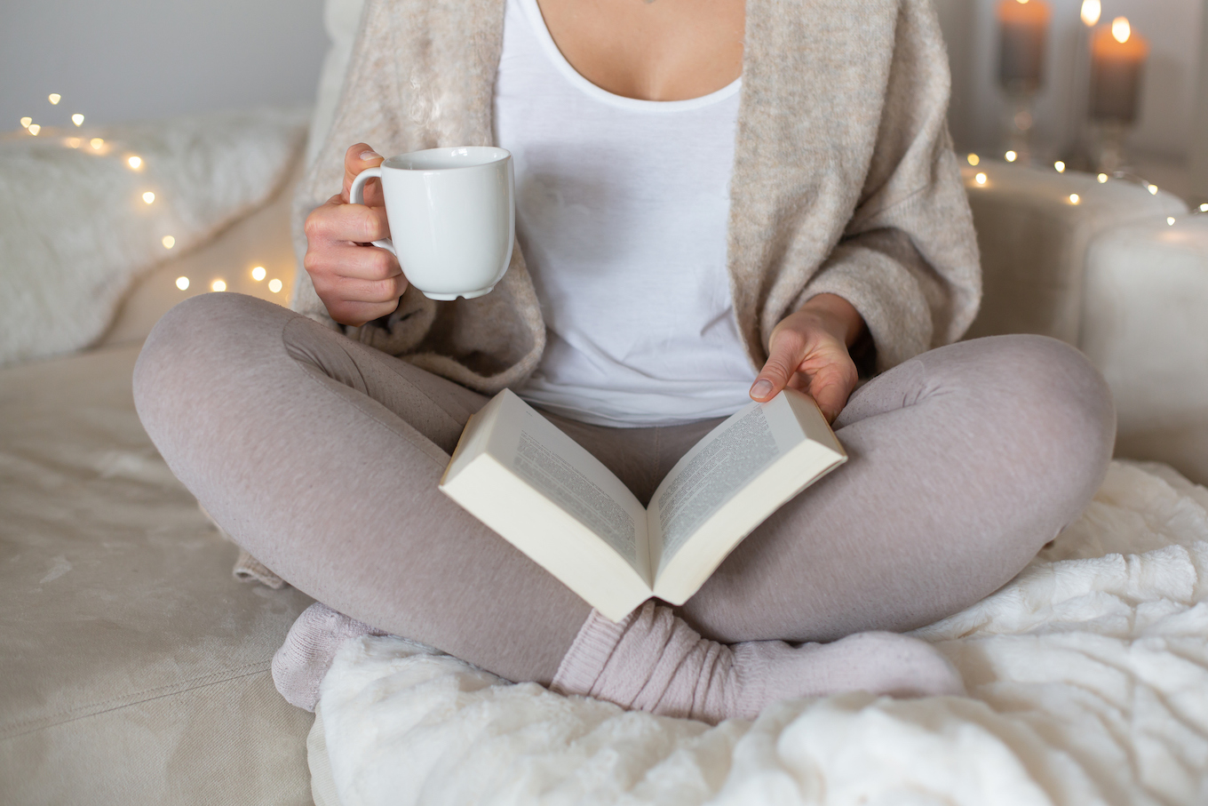 Beautiful 25 years old caucasian lady sit down on the sofa and is reading with coffee