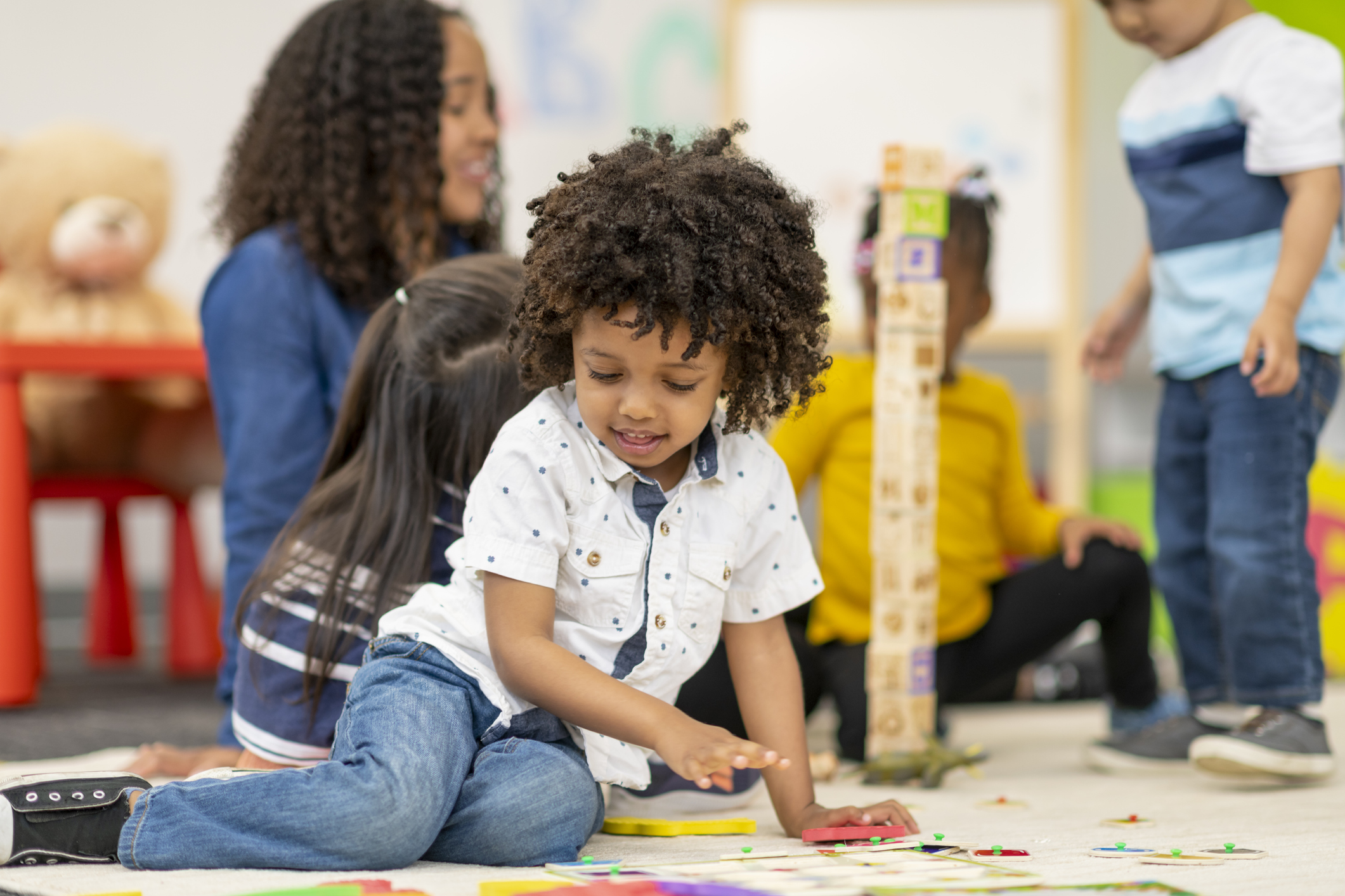 Preschool students playing in classroom with teacher