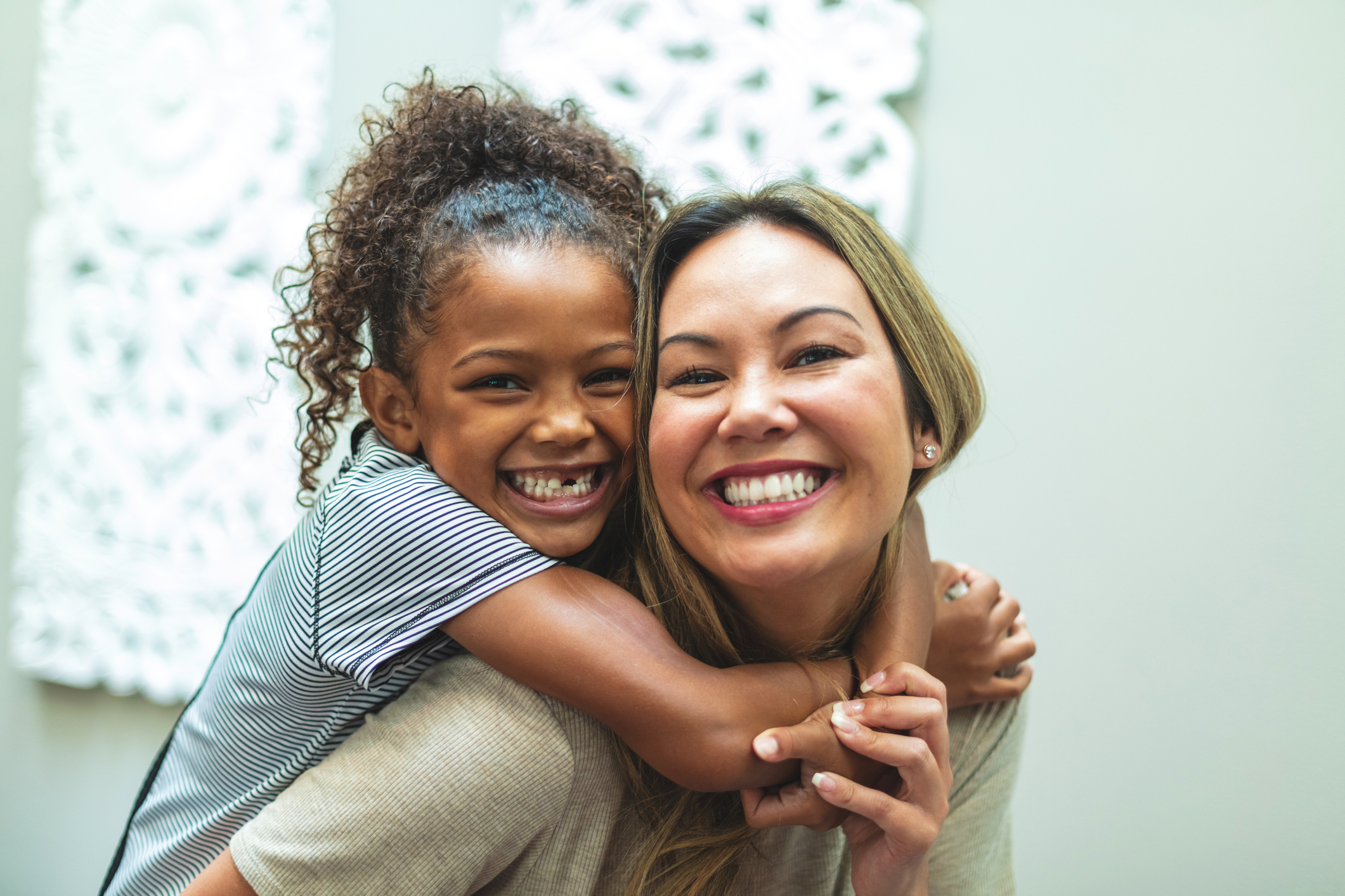 Asian Mother with daughter of mixed Chinese and African American ethnicity at home indoors posing playfully for portraits smiling and being silly