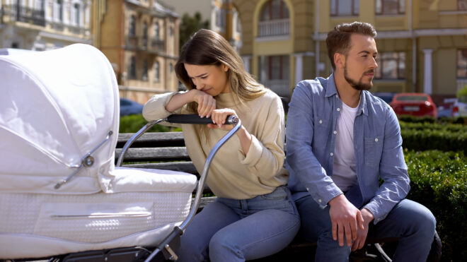 Mom staring at baby in stroller while husband looks on the other direction