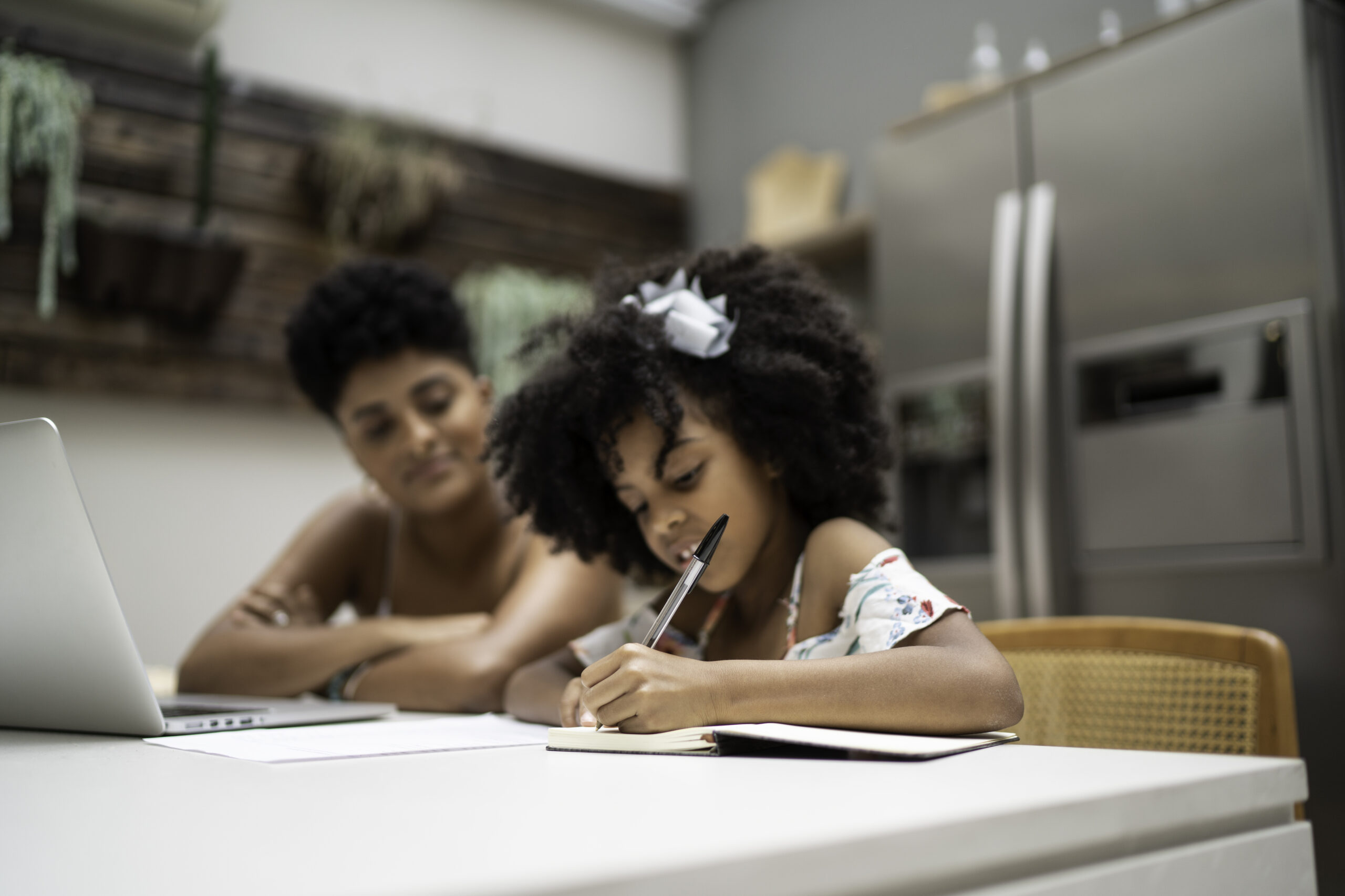 Little girl doing homework with her sister