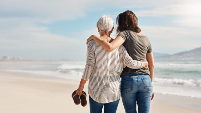 older woman and younger woman walking on beach