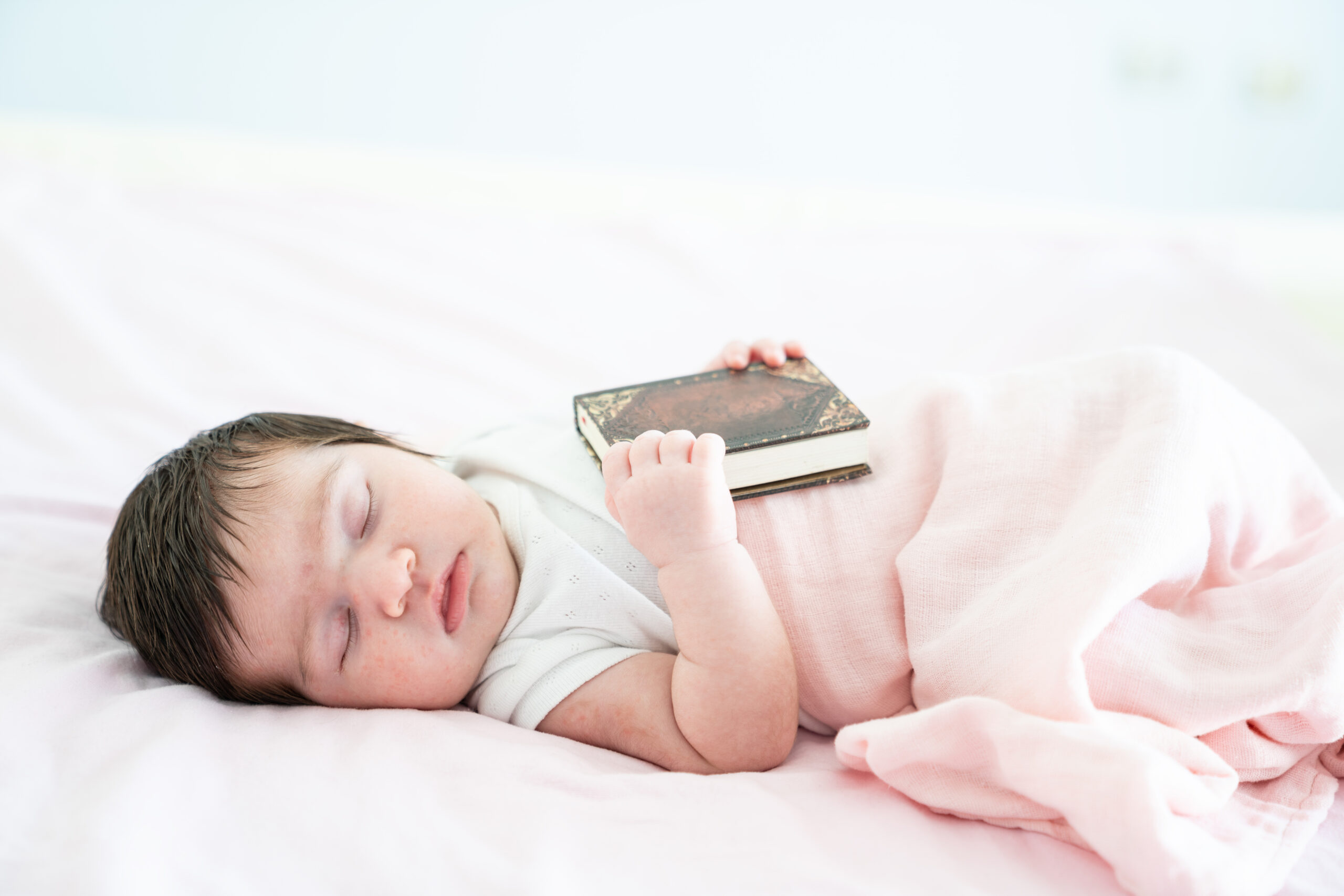 Portrait Of Sleeping Baby And Hardcover Book On Bed
