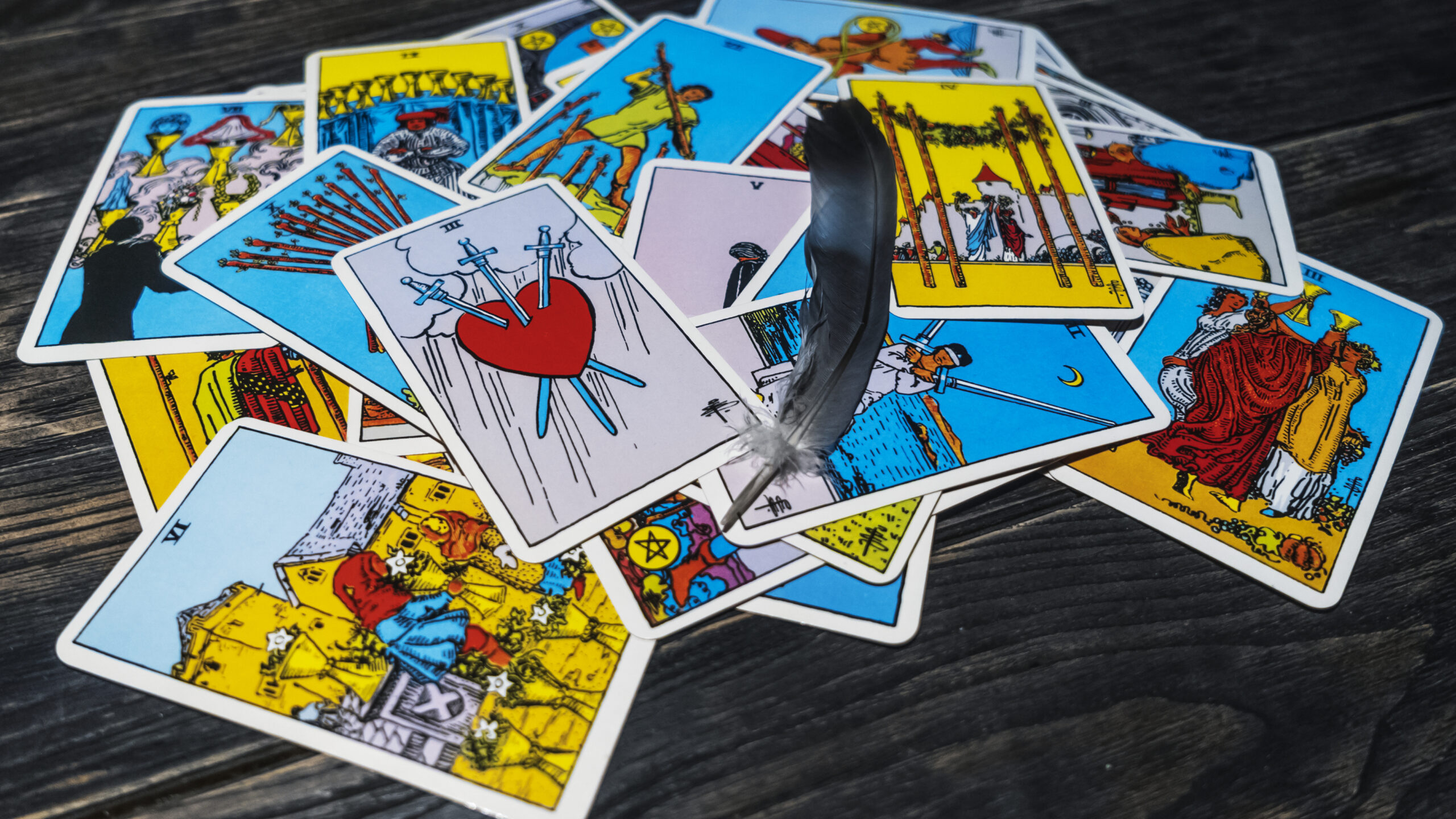 Tarot cards and bird feather on wooden background. Mystical and divination concept.