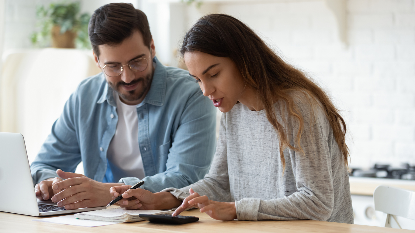 Young husband and wife using calculator laptop talking doing paperwork