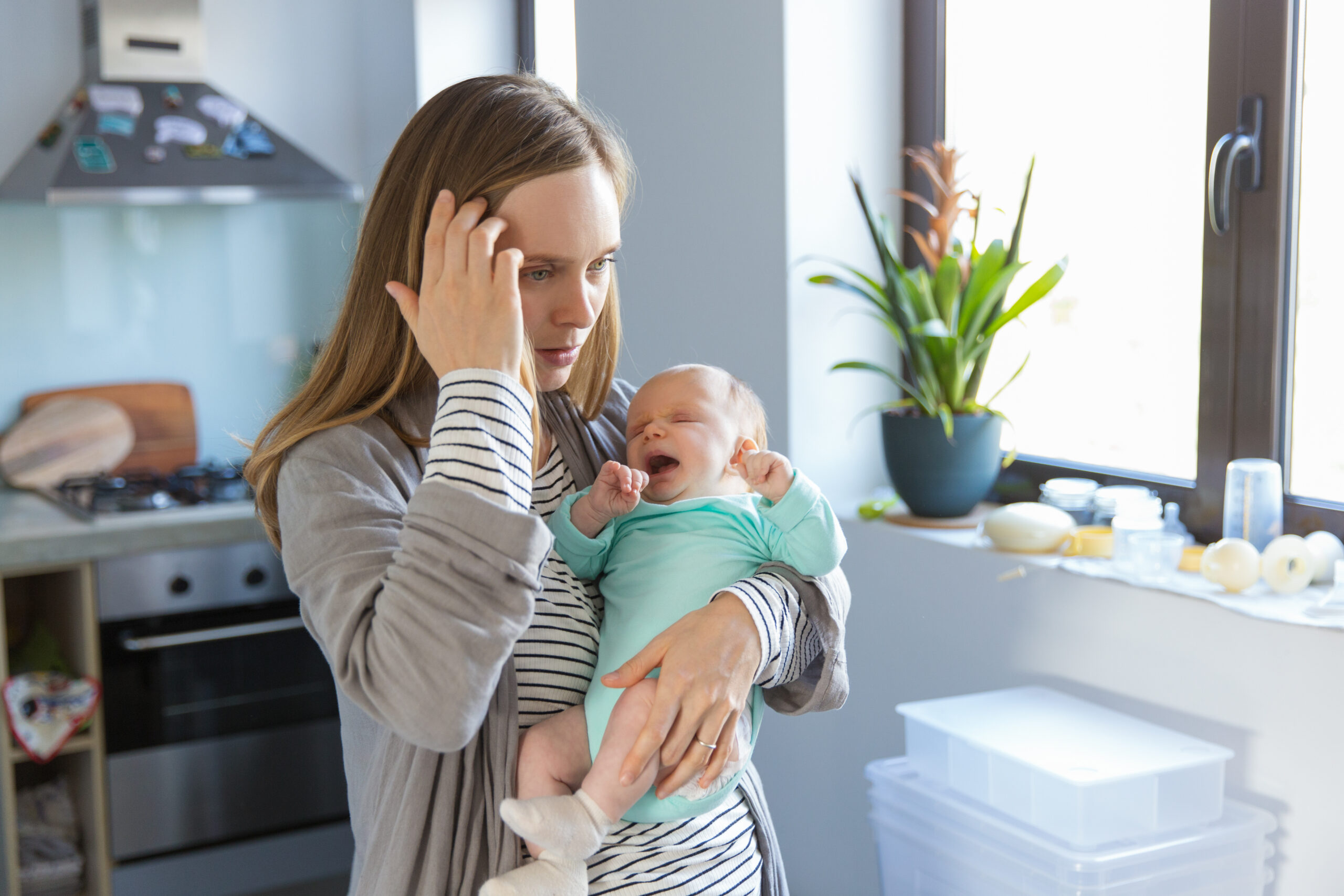 Tired concerned new mother rocking crying baby