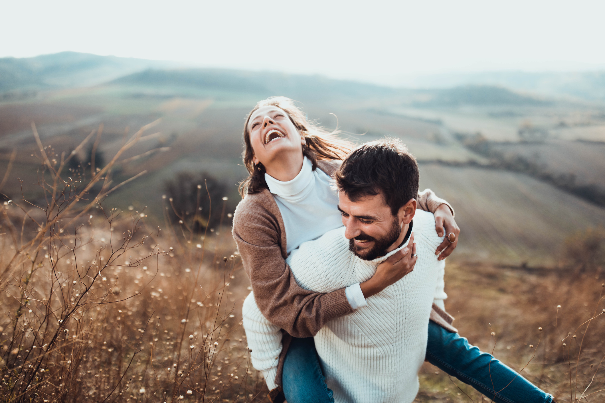 Cheerful couple having fun while piggybacking in autumn day outdoors.