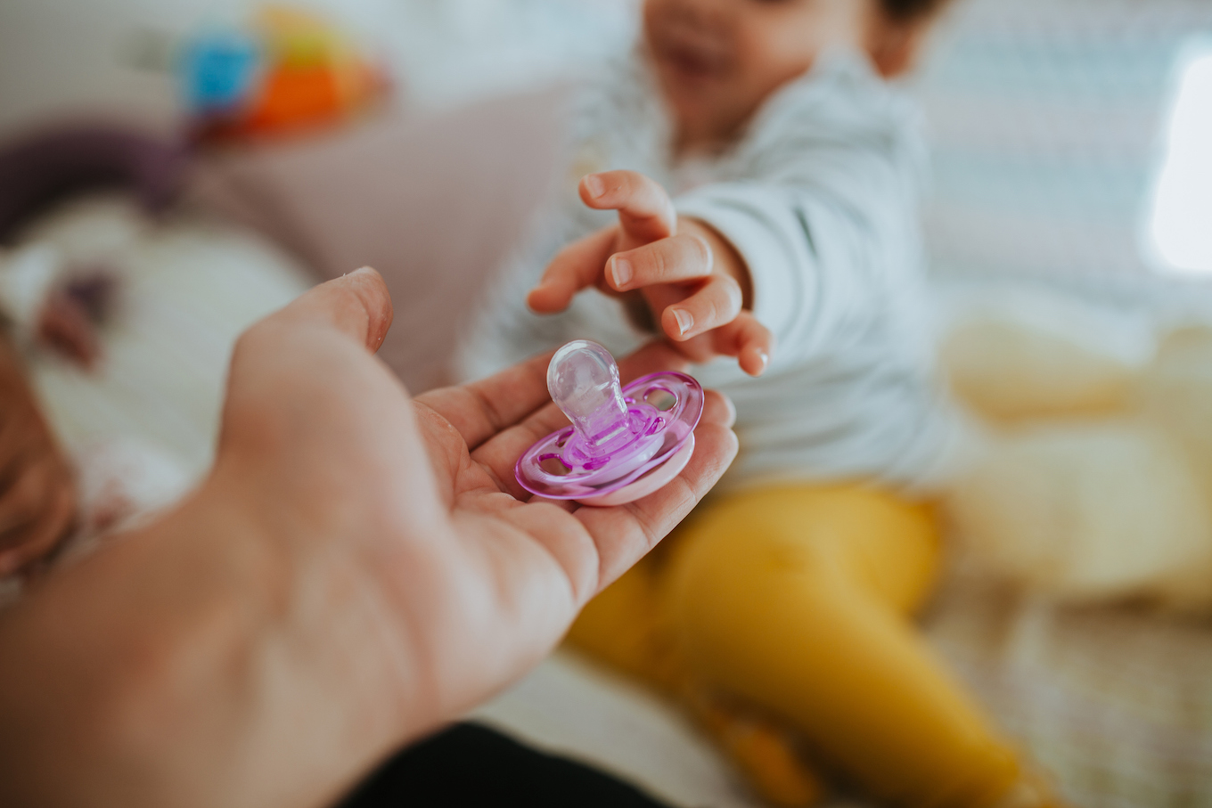Cropped Hand Giving Pacifier To Baby Girl