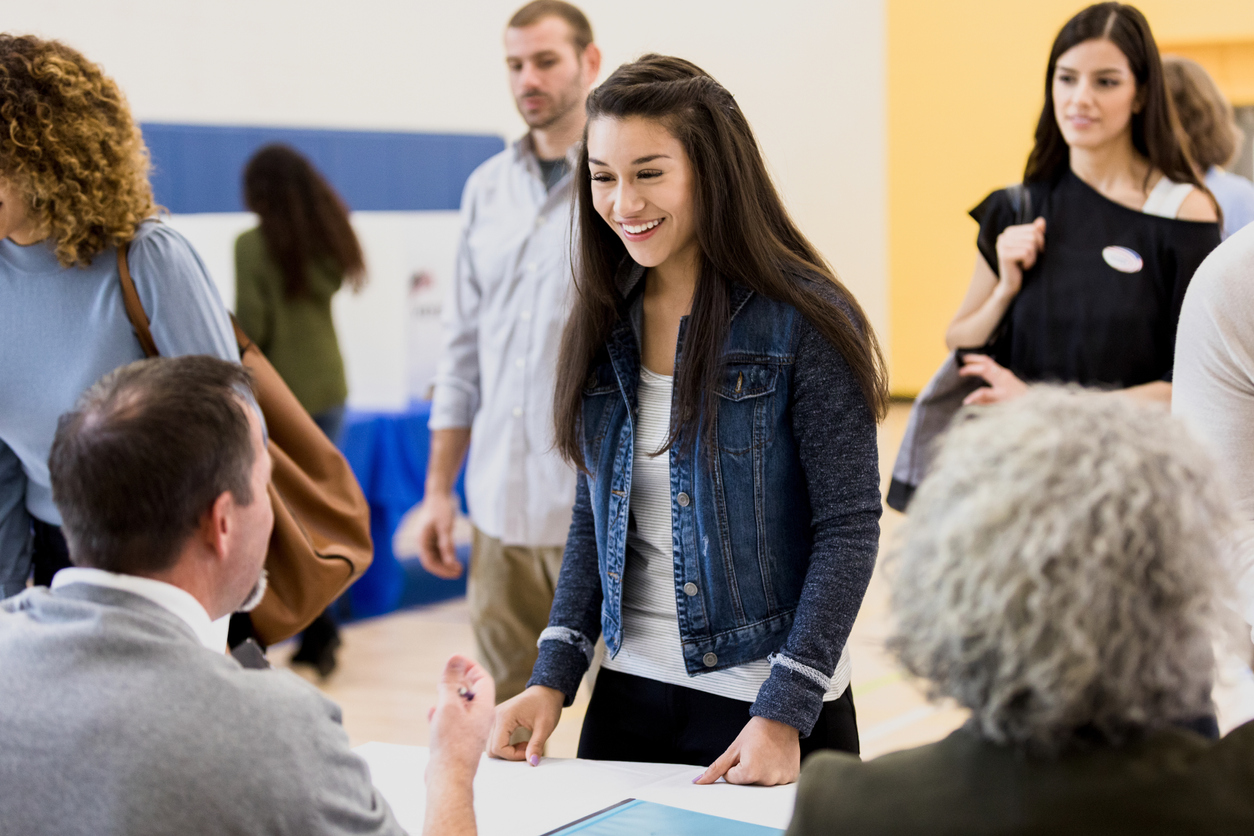 Young woman signing up to vote smiles at volunteer