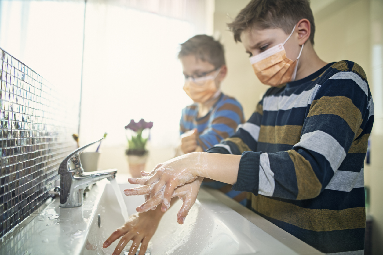 Little boys wearing face masks washing hands thoroughly