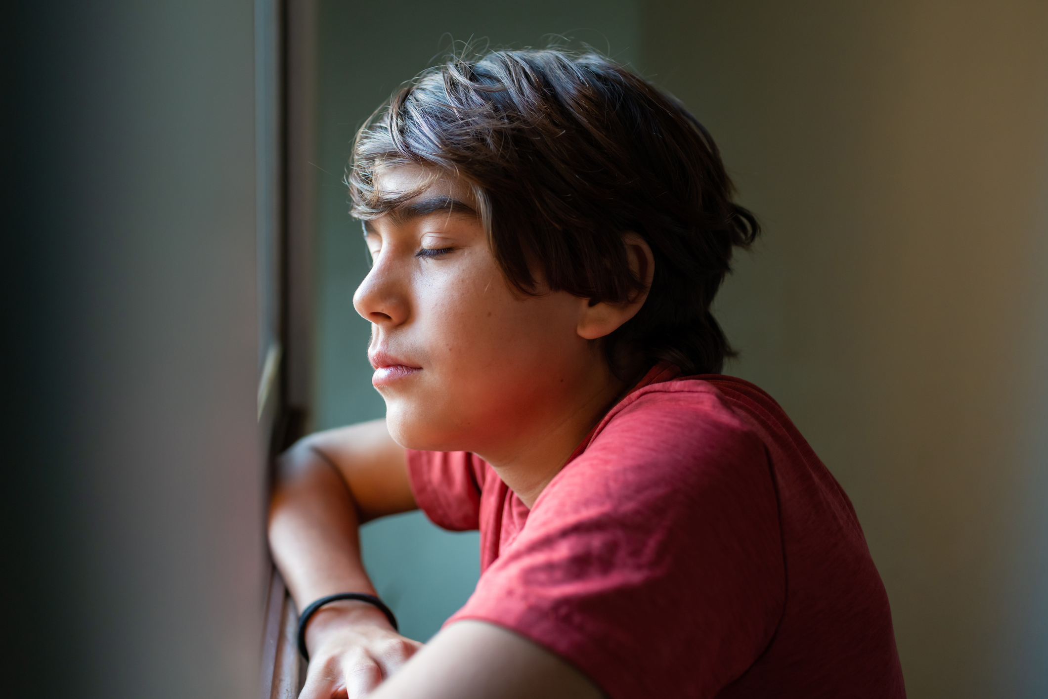latinx preadolescent boy with closed eyes, reflecting, relaxing, pensive.