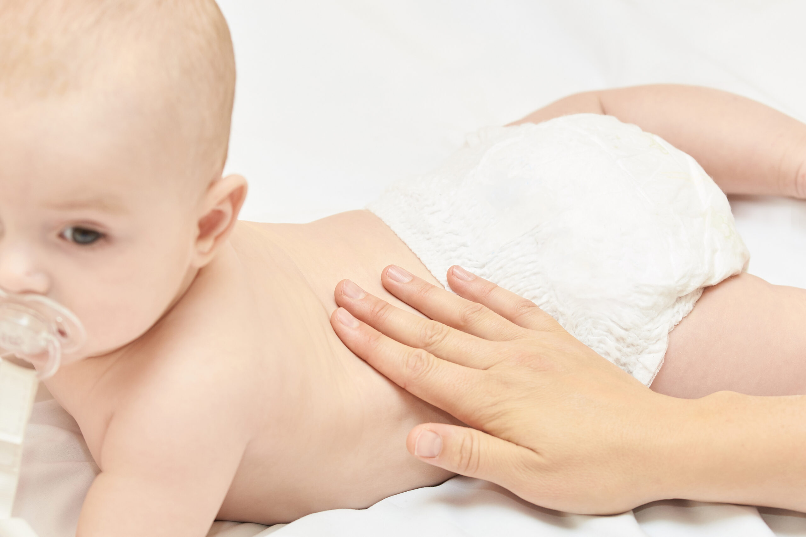 Newborn boy, mother hand. Infant mom massage. funny children change diaper. Home napkin