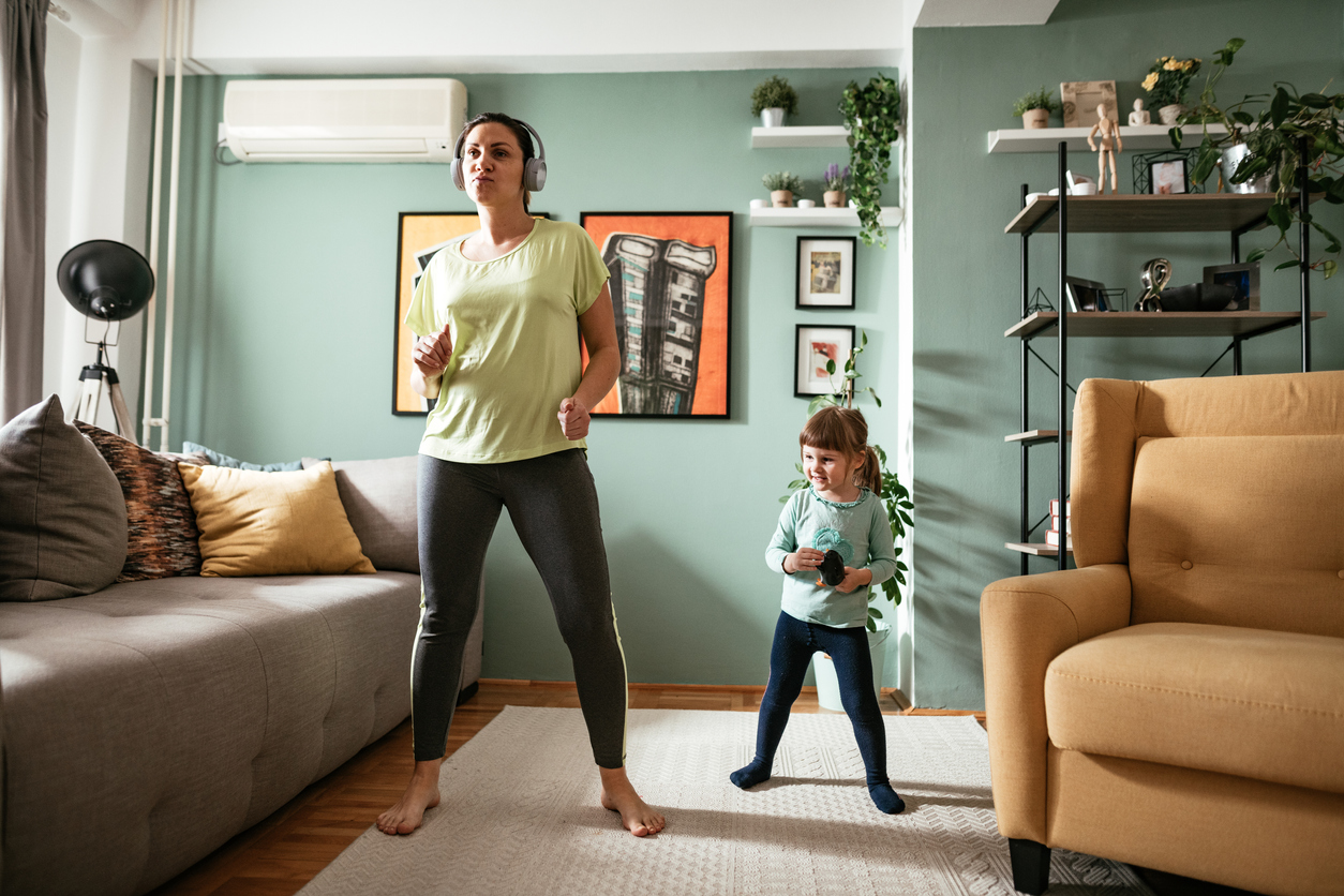 Adult woman dancing at home during quarantine with three year old daughter