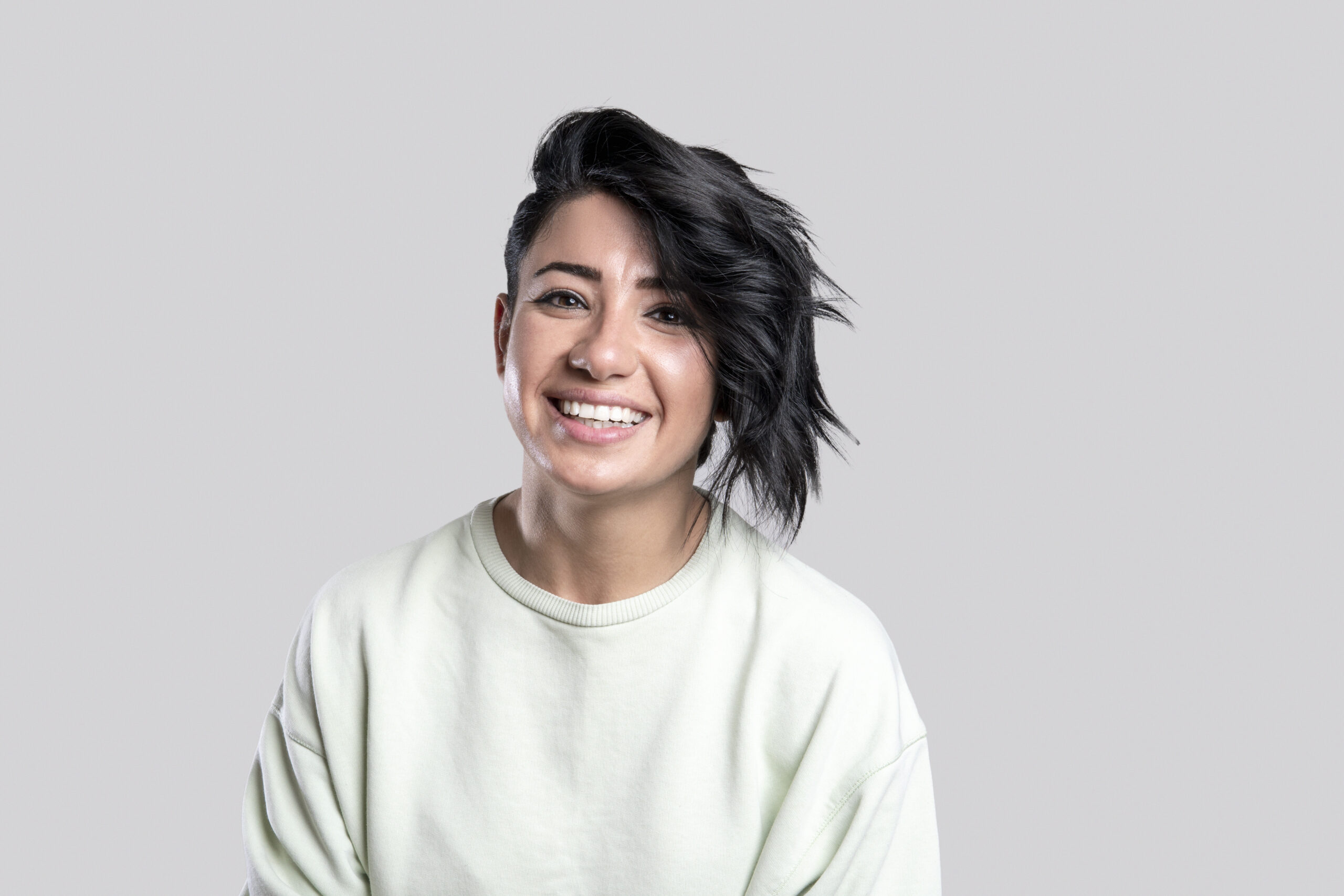 Close up photo portrait of cheerful young woman with smiling facial expression over gray background