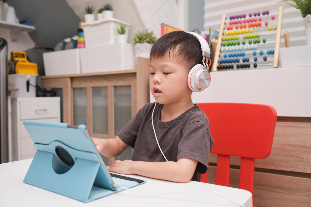 Asian 4 years old toddler boy child using tablet pc computer, Child at home during the Covid-19 health crisis, Distance Learning, Activities for Kindergarten concept