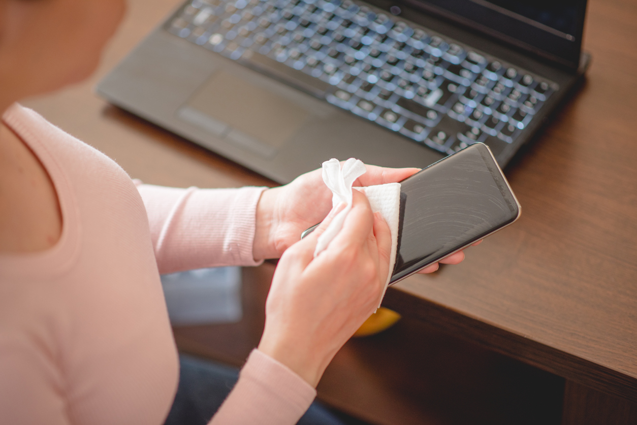 Woman wiping down smartphone with wet wipes