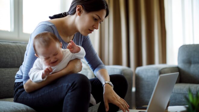 Mom tired doing work while holding a crying baby