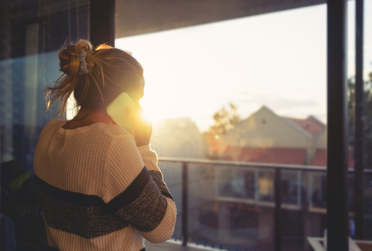 Woman looking through the window at sunset.