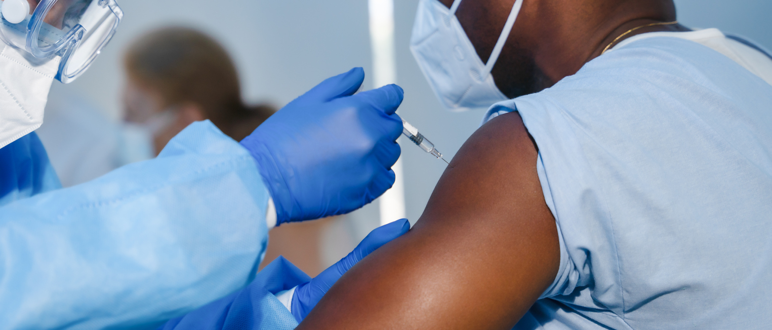 hand of medical staff in blue glove injecting coronavirus covid-19 vaccine in vaccine syringe to arm muscle of african american man for coronavirus covid-19 immunization