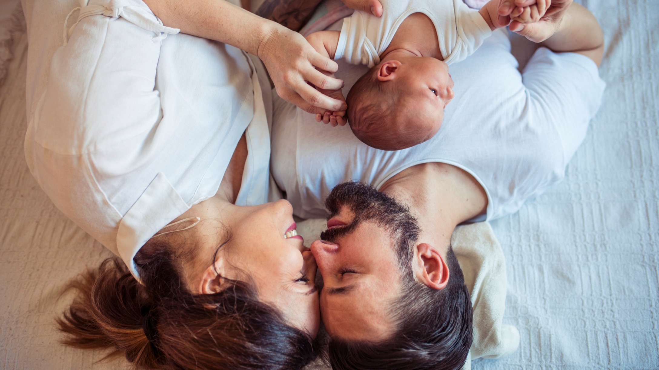 man and woman in bed with baby