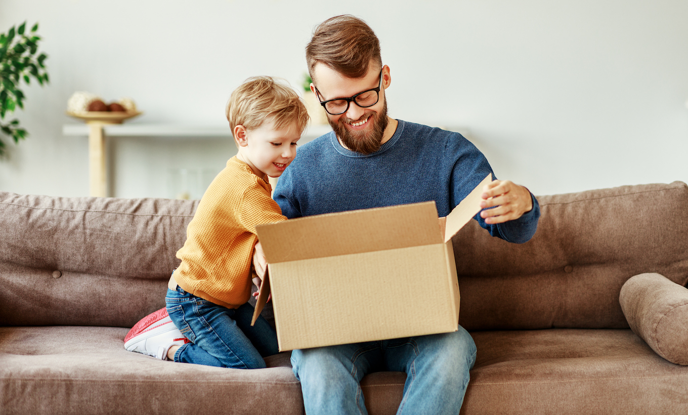 Father and son unpacking delivery box on couch
