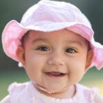 smiling baby girl dressed in a pink hat