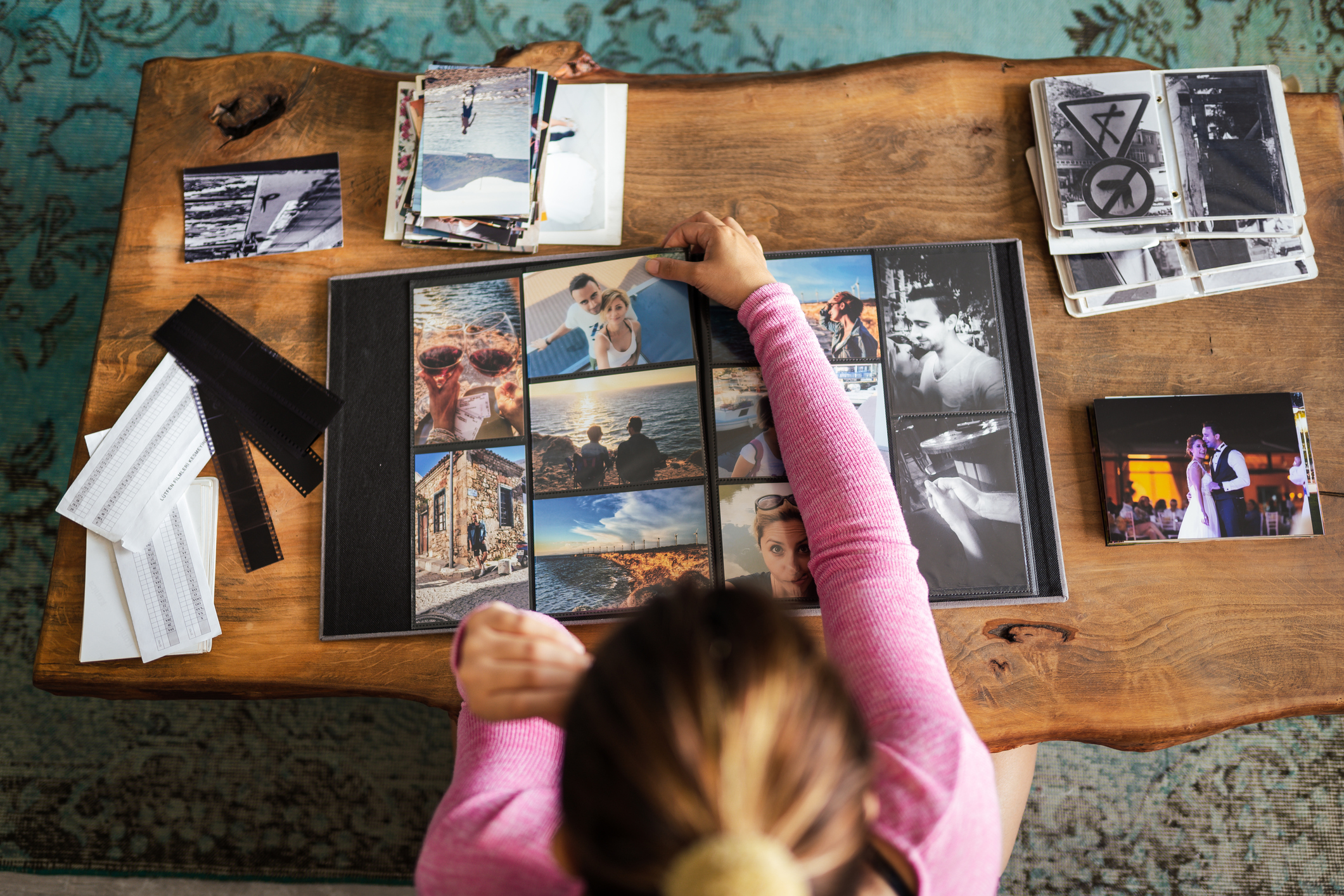 Young Adult woman adding photos to a photo album at home