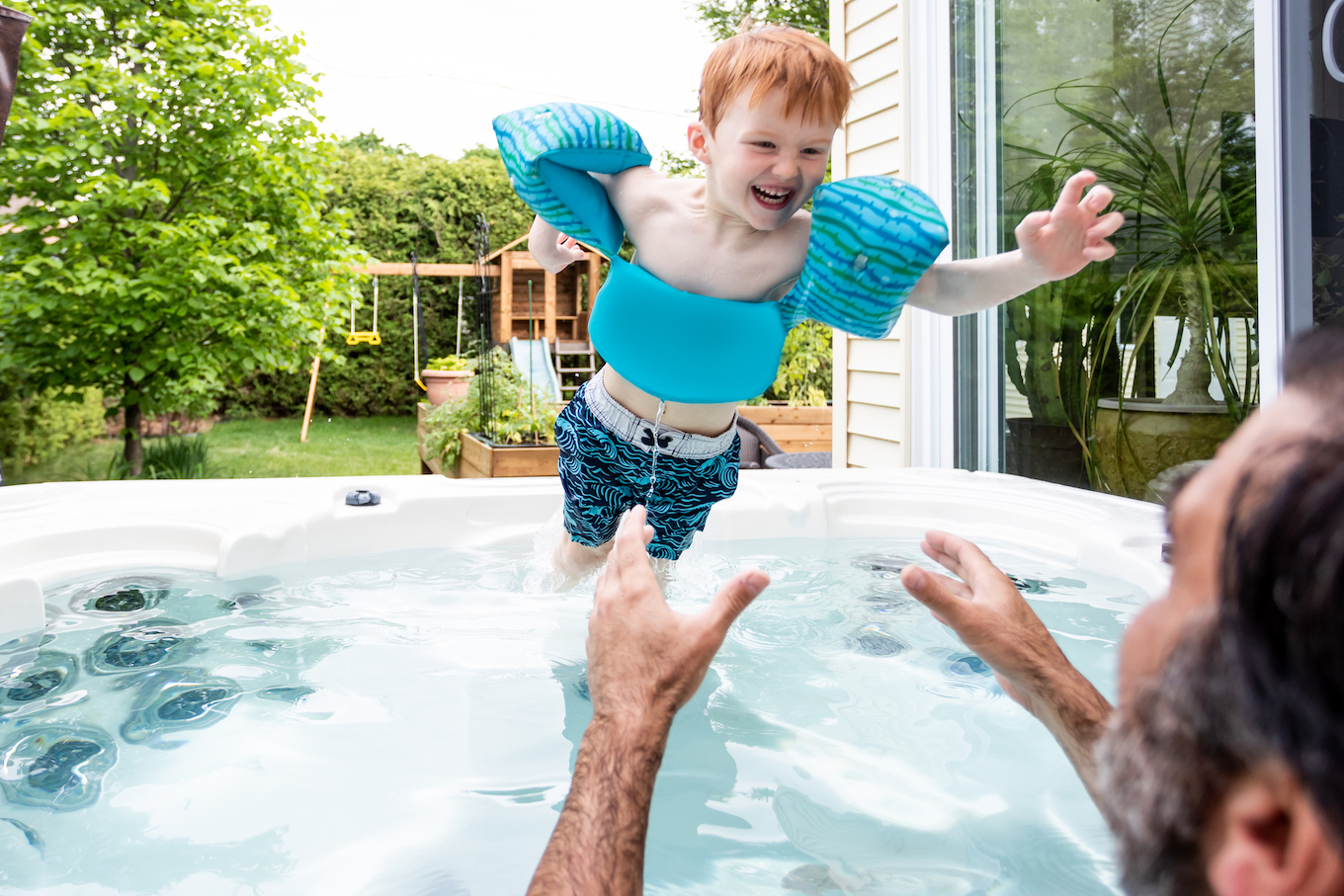 Cute Kid and Father in the Hot Tub in the Backyard in Summer