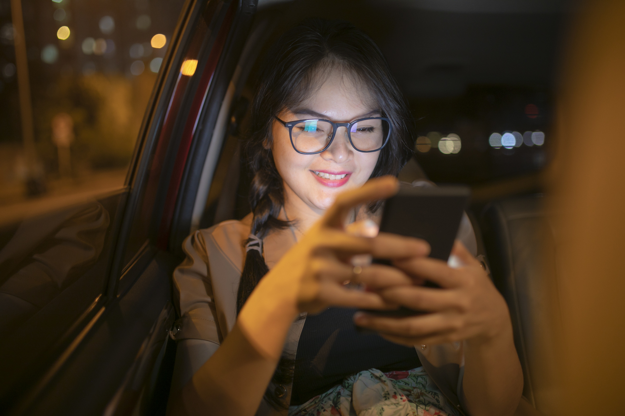 Asian woman with mobile phone in a car