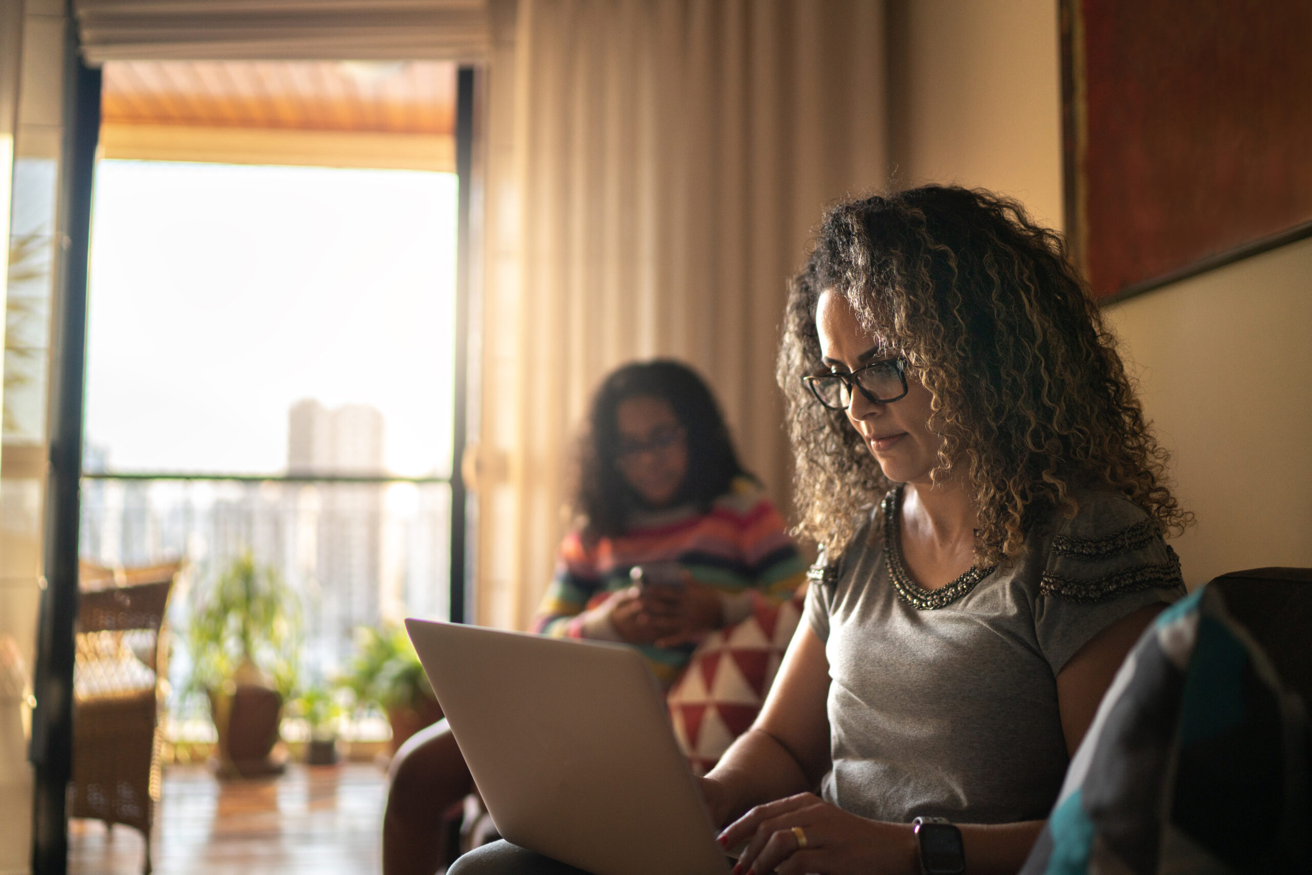 Mature woman working at home, using laptop sitting on the couch