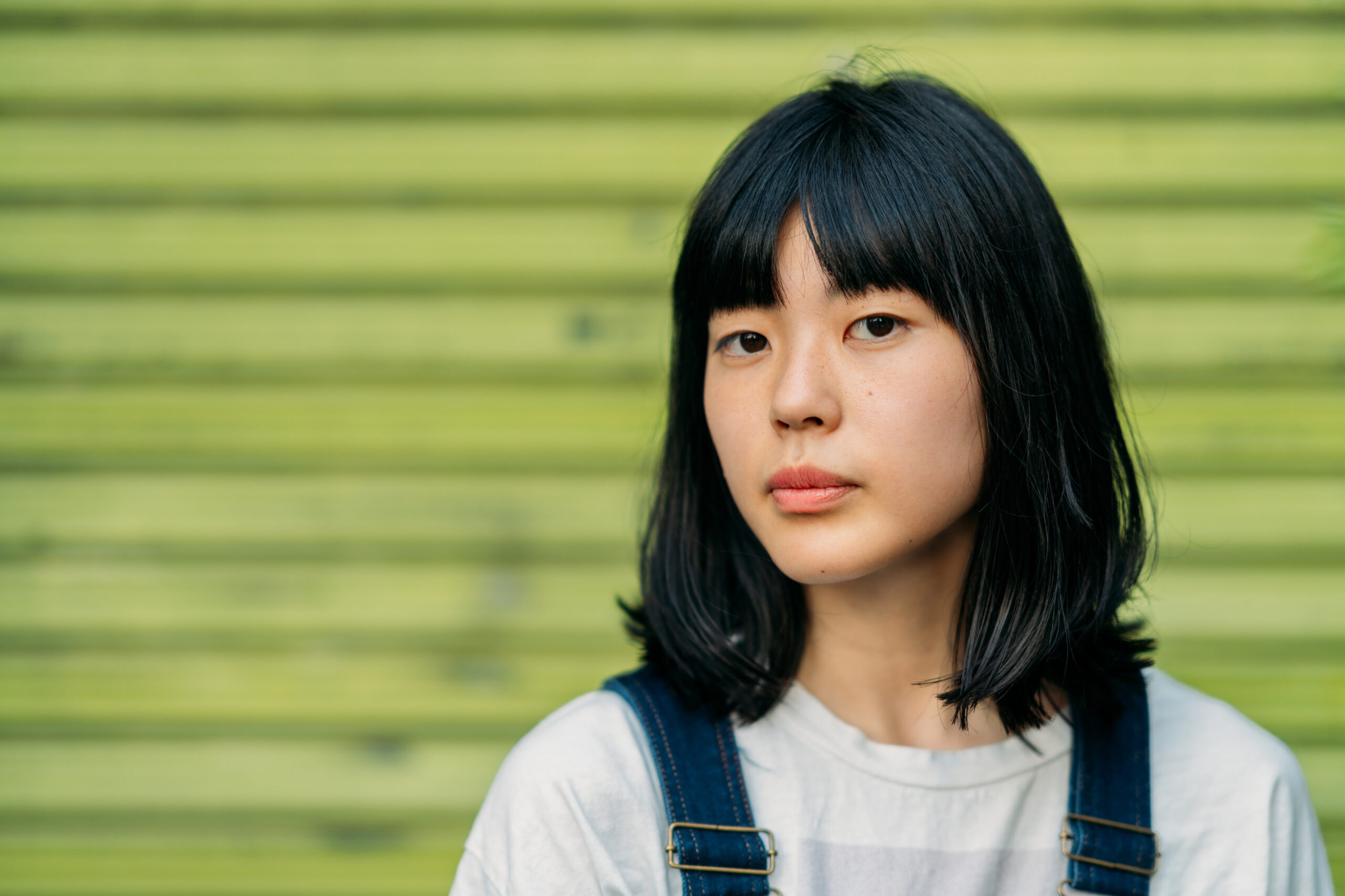 Portrait of young woman in front of green wall