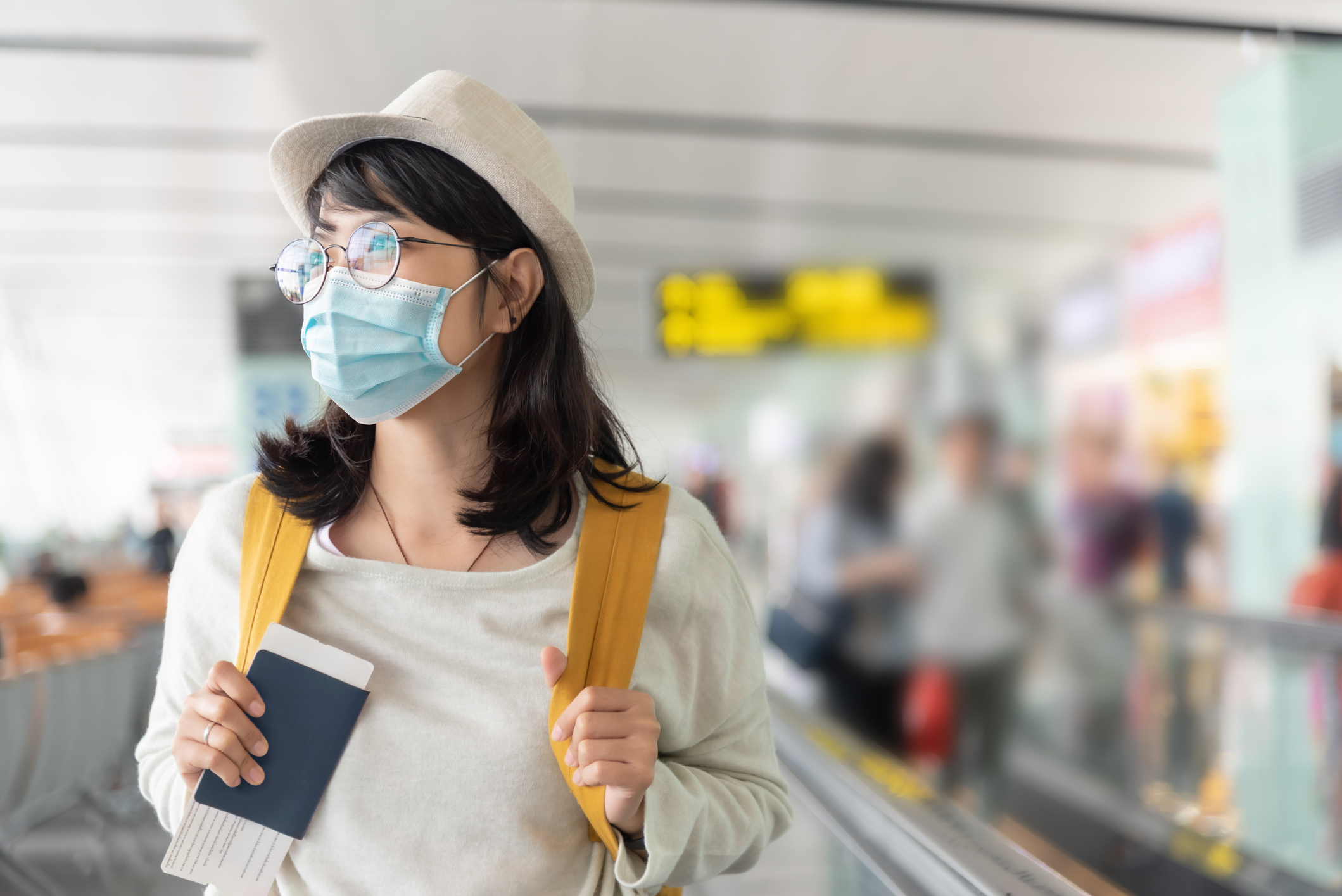 Asian woman wearing protective face mask in international airport.