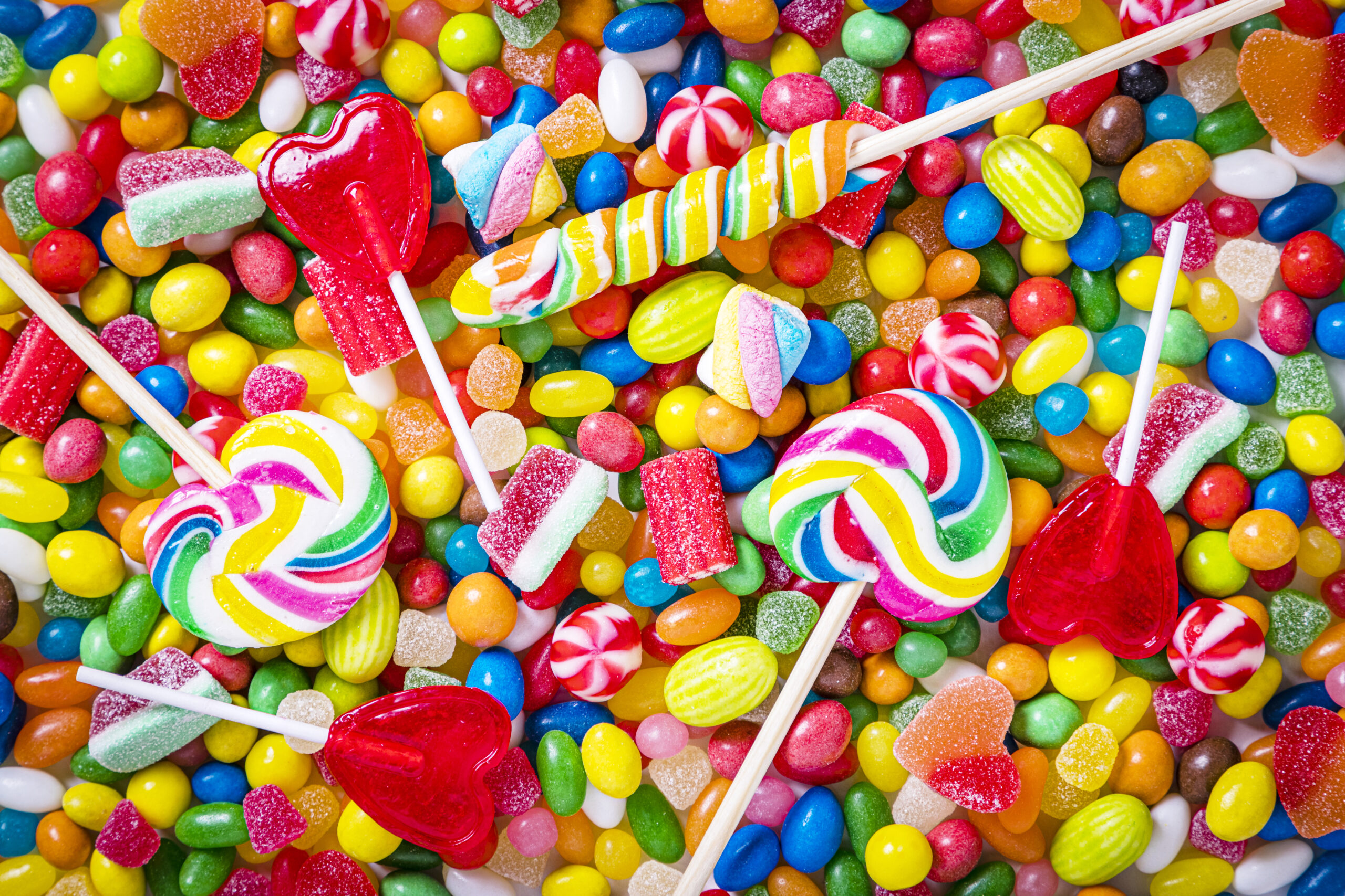 Assortment of multicolored candies, jelly beans and lollipops background