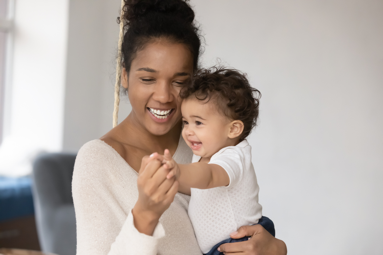 Affectionate loving african mum having fun with adorable small baby.