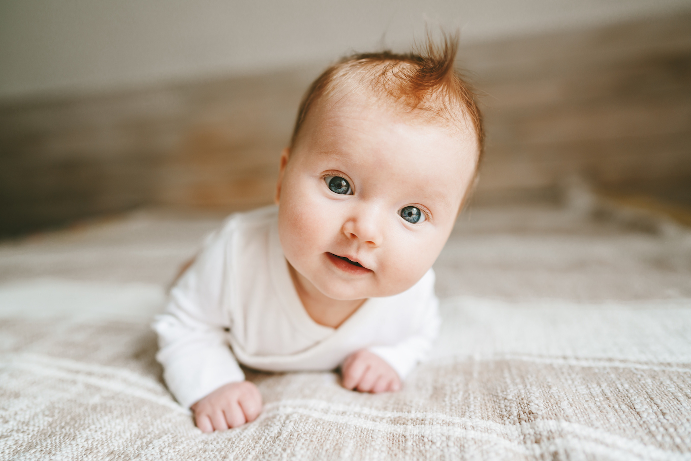 Cute baby ginger hair close up crawling on bed smiling adorable kid portrait family lifestyle 3 month old child