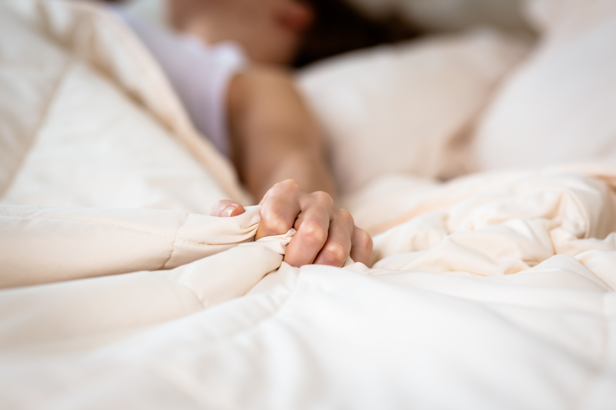 woman grabbing blanket in bed