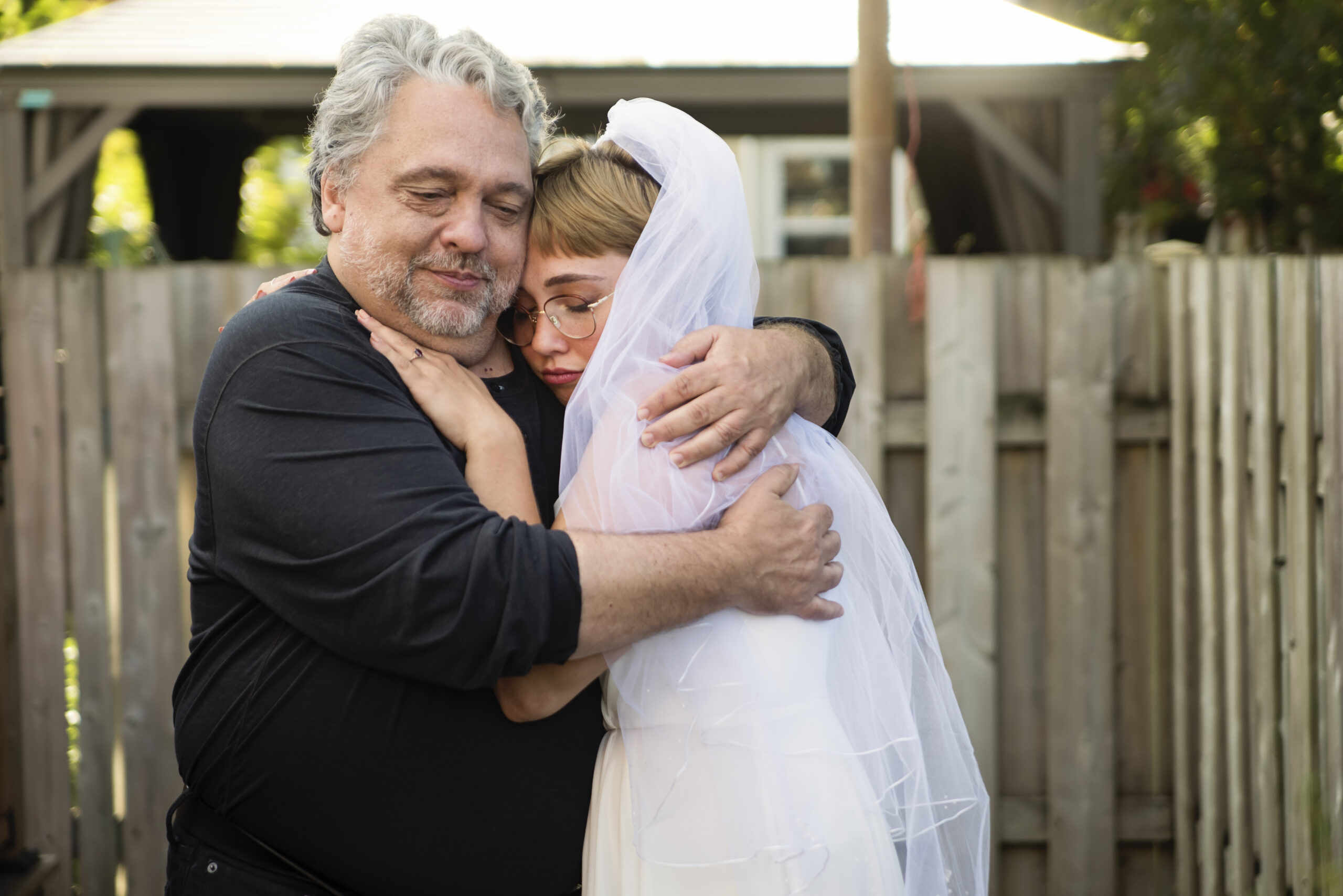 Millennial bride posing with father at wedding cocktail in backyard.