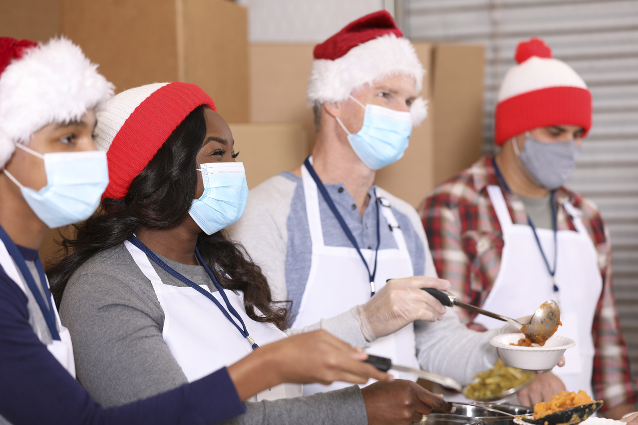 Multi-ethnic group of volunteers work at soup kitchen at Christmas.