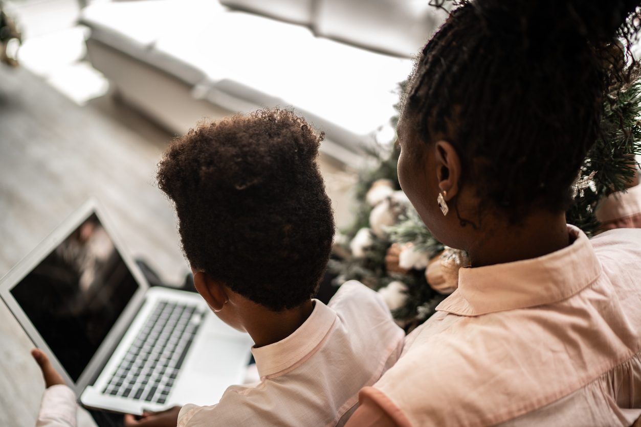 Rear view of mother and son using laptop at home