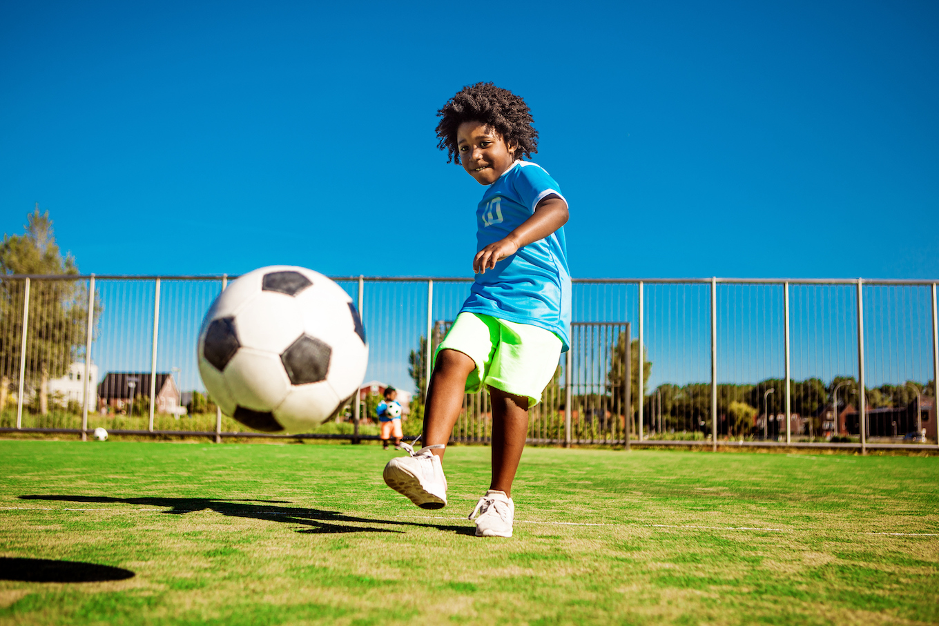 Beautiful young black boy training on the football pitch