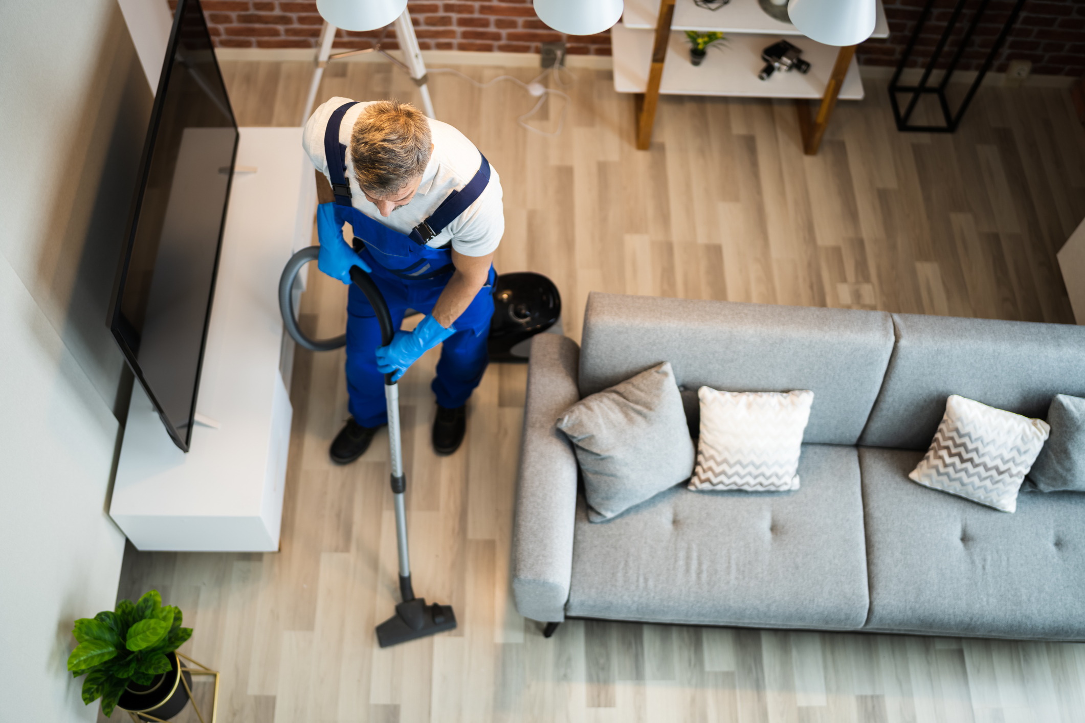 Man In Uniform Vacuuming House Floor