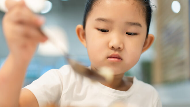 young Asian girl taking bite of lunch