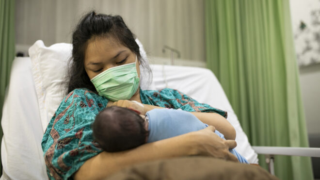 mom wearing a face mask holding a baby