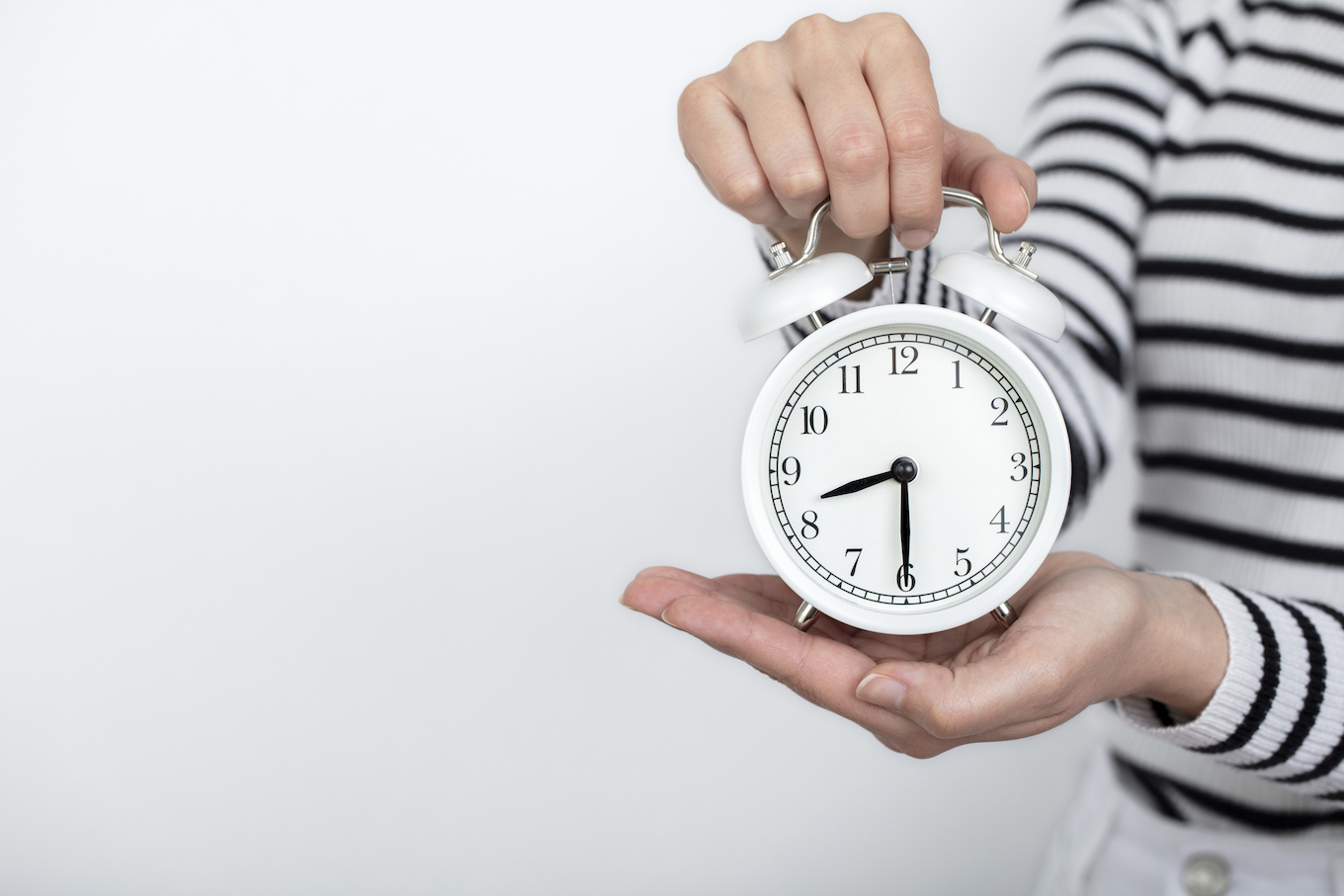 working time. return to work. woman holding clock in hand. isolated background.