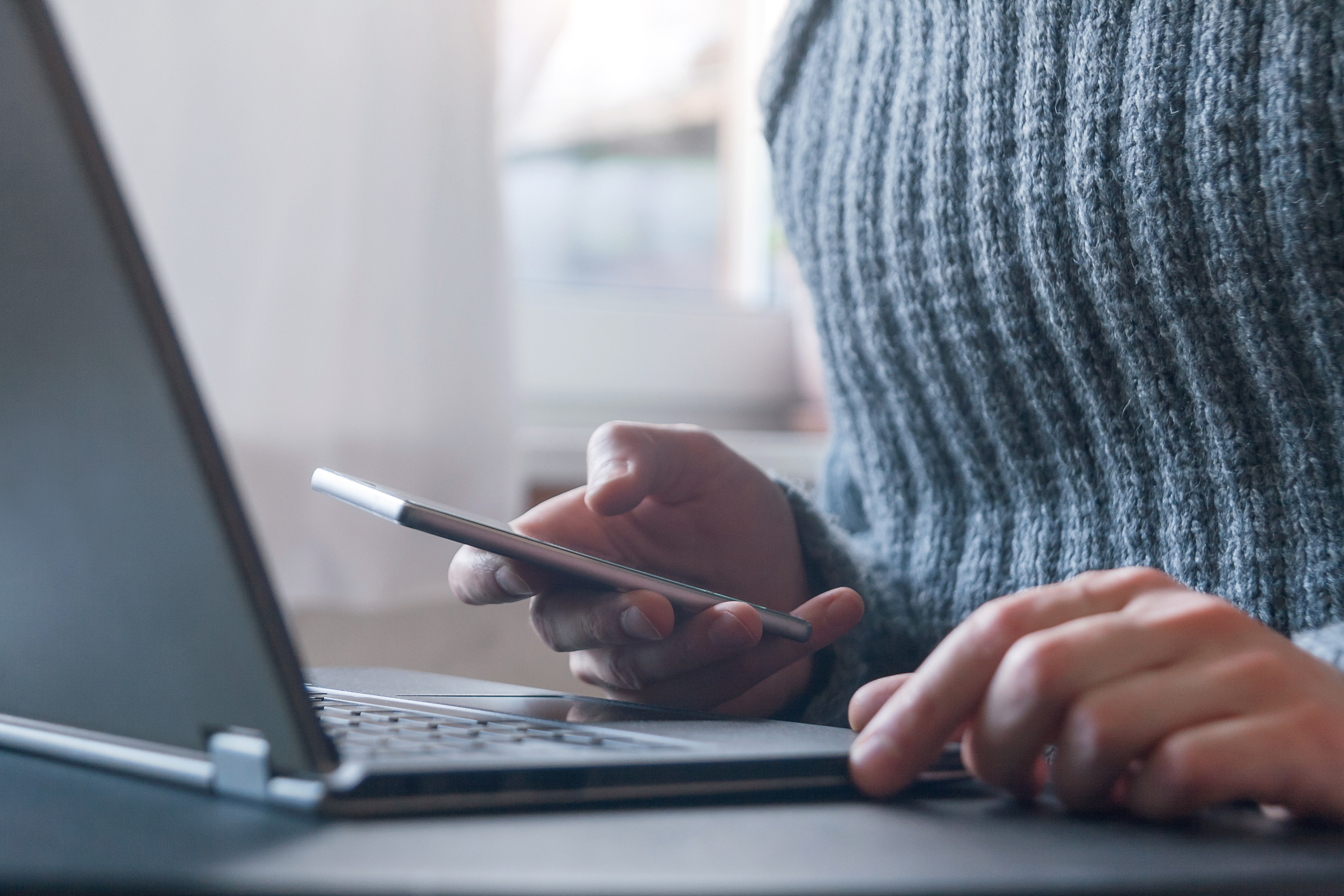 two steps verification, sms code for authorization, unrecognizable man using laptop checking smart phone