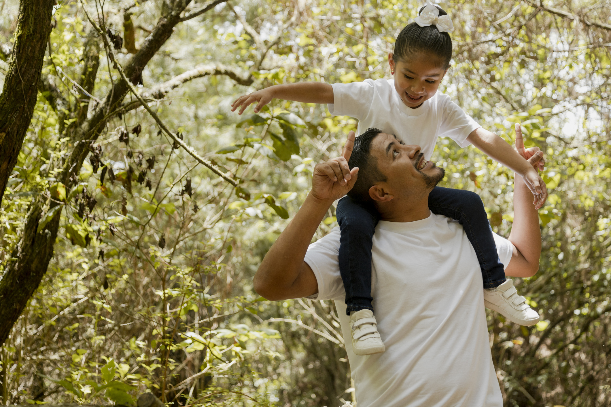 Latin dad carrying his daughter on his shoulders-Family walking in the park-father playing with his daughter in the park