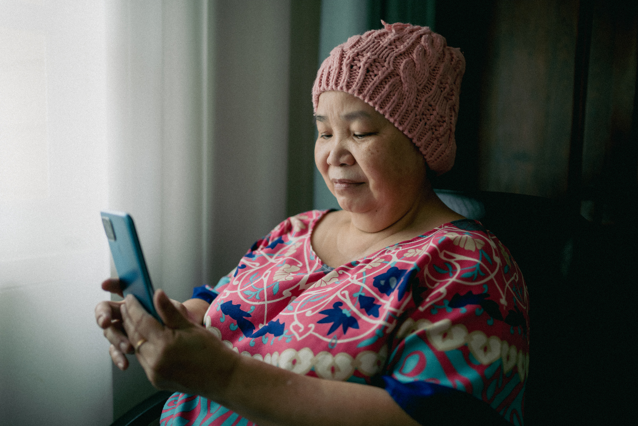 Portrait of asian senior woman with cancer using smart phone
